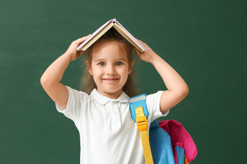 Little schoolgirl with book on color background