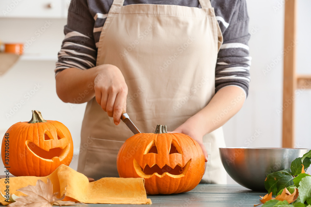 Wall mural Woman carving pumpkin for Halloween at table