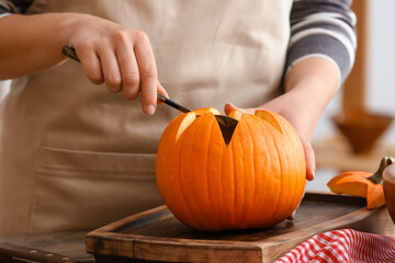 Woman carving pumpkin for Halloween at table