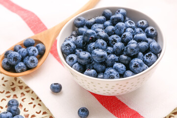 Bowl and spoon with tasty ripe blueberry on table