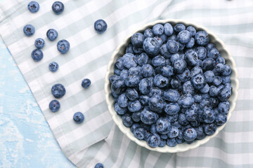Bowl with tasty ripe blueberry on table