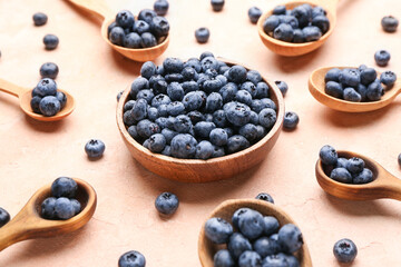 Plate and spoons with tasty ripe blueberry on color background