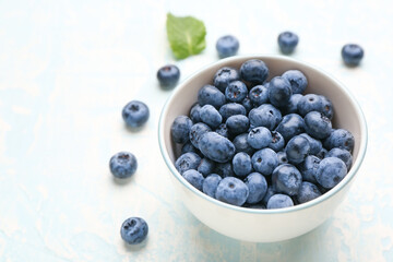 Tasty ripe blueberry in bowl on light background