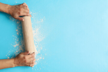 Female hands hold rolling pin on blue background