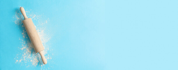 Rolling pin and flour on blue background