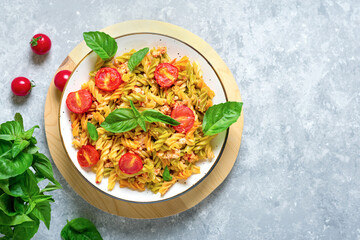 Fusilli - classic italian pasta from durum wheat with chicken meat, tomatoes cherry, basil in tomato sauce in white bowl on gray concrete table Mediterranean cuisine Top view Flat lay