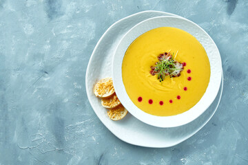 Pumpkin cream soup with octopus and croutons in a white bowl on a gray background. Creamy seafood soup