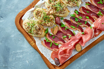 Plate with different types of meat antipasto - sliced prosciutto, chorizo, jerky duck and...