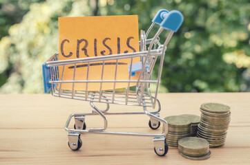 Crisis lettering on sticker / shopping trolley and stacks of coins. Financial concept. The concept...