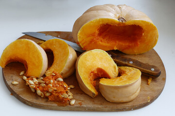 half pumpkin and cut with knife on kitchen board closeup photo