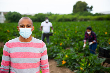 Portrait of latino farmer in protective mask on the field