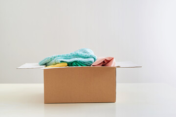Donation box with clothes on table against white background