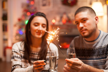Happy couple on christmas day holding hand fireworks.