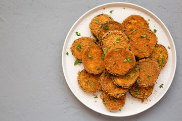 Homemade Garlic Parmesan Baked Eggplant on a plate over gray surface, top view. Flat lay, overhead, from above. Copy space.