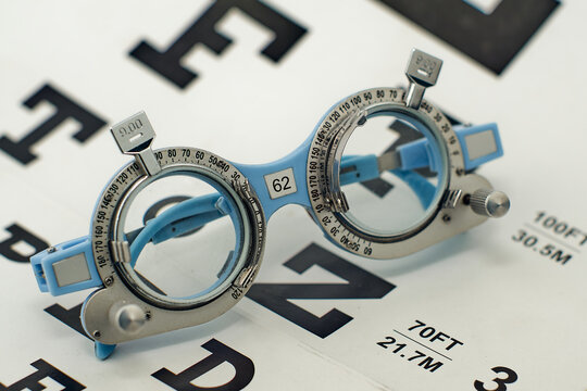 trial frame with set of corrective lens with snellen charts background