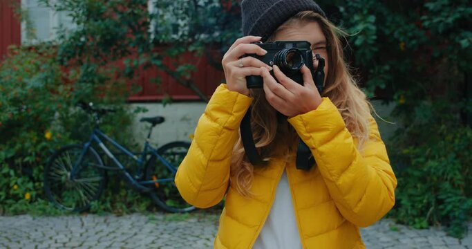 Cinematic shot of pretty young woman make photos on vintage old analog film camera. Road trip and adventure wanderlust concept. Digital nomad or urban millennial content creator