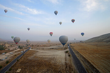 Colorful hot air balloon ride and tour in Goreme valley, semi-arid region in central Turkey known for its distinctive fairy chimneys, tall, cone-shaped rock formation- Cappadocia, Turkey