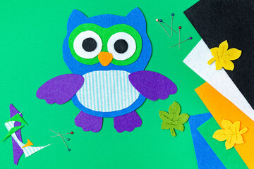 Craft, applique of an owl from multi-colored felt. Creative classes with children. Sewing soft toys, hobby.