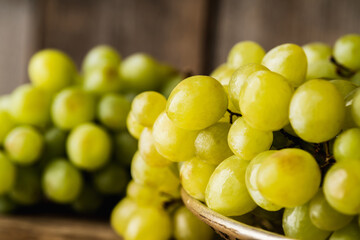 Ripe bunch of green grapes washing on vintage metal colander. Selective focus. Shallow depth of field.