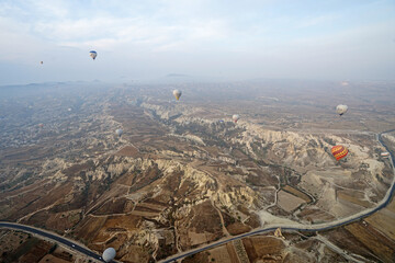Colorful hot air balloon ride and tour in Goreme valley, semi-arid region in central Turkey known for its distinctive fairy chimneys, tall, cone-shaped rock formation- Cappadocia, Turkey
