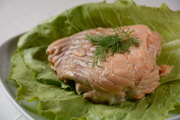 Canned salmon chunks with lettuce leaves,on white plate