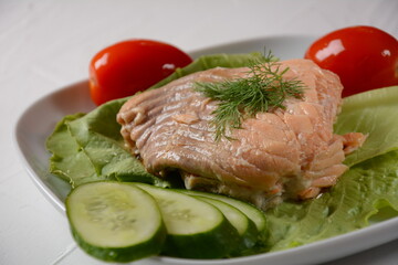 Canned salmon chunks with lettuce leaves,on white plate