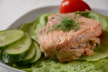 Canned salmon chunks with lettuce leaves,on white plate