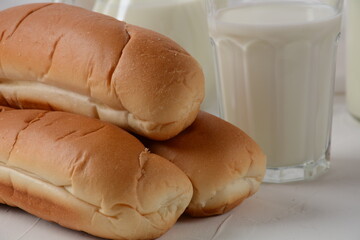 Fresh buns and milk on white background