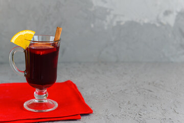 Mulled wine with cinnamon and orange in a cup on a gray background. Horizontal orientation, copy space.