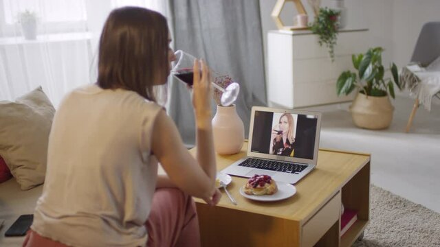 Modern young woman spending time at home during self isolation period having online meeting with her best friend using laptop