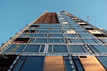Sichtbarer Baufortschrittt am Neubau eines Hochhaus mit Glasfassade im Licht der Abendsonne im...