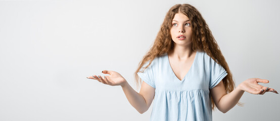 Confused girl spreads hands sideways, feels doubt while makes choice. Human emotions concept