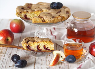 Home cooking. Cut piece of Apple and plum pie Charlotte on a wooden white background for tea.