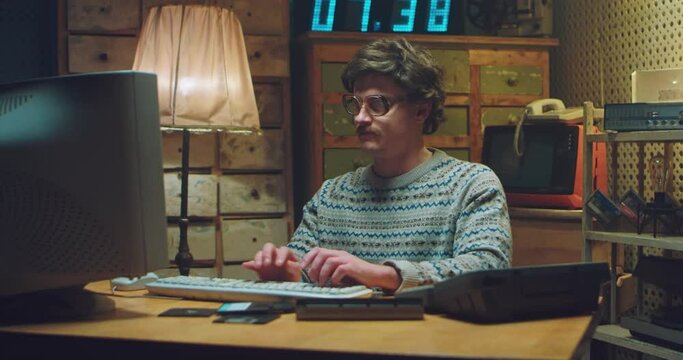 Caucasian male nerd in glasses with mustache sitting at desk in retro room and working on computer. Man programist typing on keyboard and getting nervous. Vintage style of 90's. Error or failur.