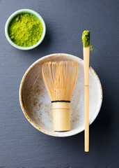 Matcha, green tea ceremony set, bowl, bamboo whisk and spoon. Grey background. Top view.