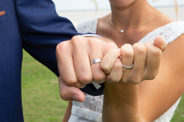 Obraz na płótnie Canvas bride and groom present their fists with the wedding rings on their fingers after celebration