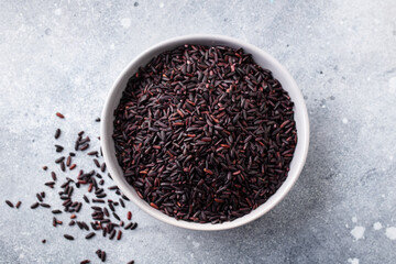 Black wild rice in a bowl. Grey stone background. Close up. Top view.