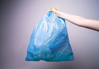 woman's hand holding a blue trash bag