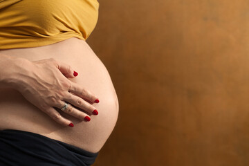 Kobieta w ciąży obejmująca swój brzuch. - obrazy, fototapety, plakaty