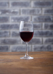 Glass of red wine on stone wall background. Wooden table. Close up.