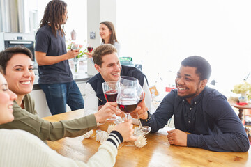 Glückliche Gruppe Freunde beim Anstoßen mit Glas Rotwein