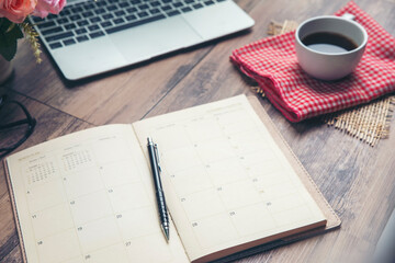 Calendar and Laptop for Planner to plan reminder daily appointment timetable, appointment, organization and meeting agenda of job on wooden desk, work from home. Coffee, book, computer place on table