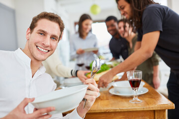 Mann hält Teller und Löffel beim Tisch decken in WG Küche