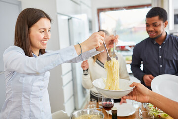 Frau beim Spaghetti servieren bei Mahlzeit mit Freunden