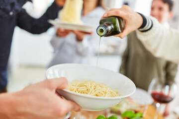 Leute gießen Olivenöl auf Spaghetti im Teller