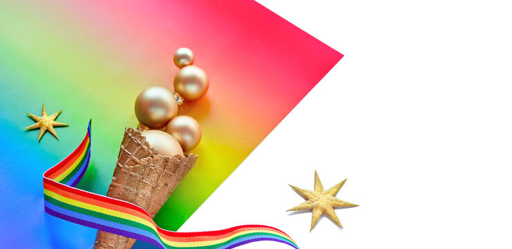 Christmas decorations in LGBTQ community rainbow flag colors, border design for panoramic greeting banner. Ice cream cone, golden baubles on rainbow paper, LGBT symbol.