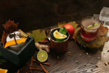 Autumn fruit alcoholic cocktails with apple, lime, orange and cinnamon on the table in restaurant