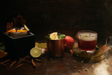 Autumn fruit alcoholic cocktails with apple, lime, orange and cinnamon on the table in restaurant