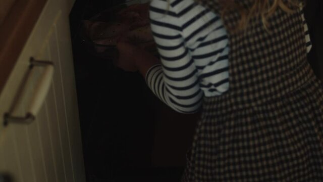 Children Placing The Prepared Flavored Chicken Legs Dish Into The Oven. - Wide Shot
