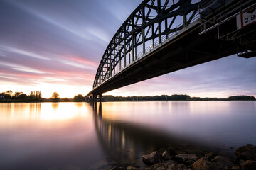 Fototapeta na wymiar Striking arch bridge spans the river during the sunrise